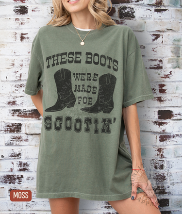 A woman wearing a green t-shirt with a graphic design of a pair of boots and the text